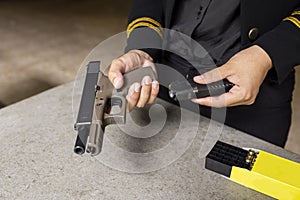 Two hand reloading law enforcement pistol in academy shooting range, focus at front gun sight