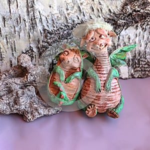 Two handmade dolls of green mama and baby dragons with wings on birch bark background