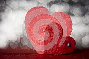 Two handmade felt red and pink hearts pierced with a pin on beautiful bokeh background. Vintage style. Love Valentine`s Day concep