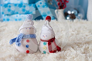 Two handmade snowmen with Christmas background on white fur