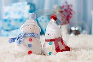 Two handmade snowmen with Christmas background on white fur