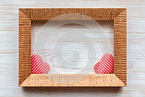Two handmade striped fabric red hearts in wooden frame on vintage white painted wooden background