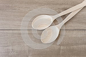 Two handmade wooden spoons on wooden background, top view. Selected focus