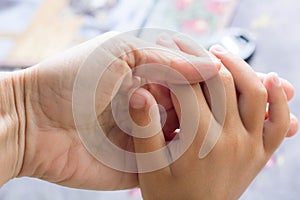 Two hands of adult and child holding together