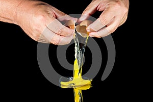 Two hands break egg on black background