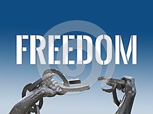 Two hands breaking chains with a white colored text `Freedom` photo