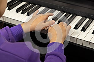 Two hands of a child playing the piano. Selective focus on children& x27;s fingers and piano keys for playing the piano.