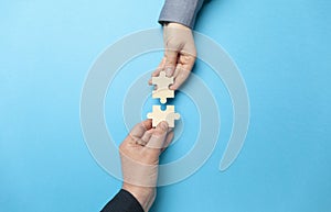 Two hands connect puzzles on a blue background. Cooperation and teamwork in business. Collaboration people for success