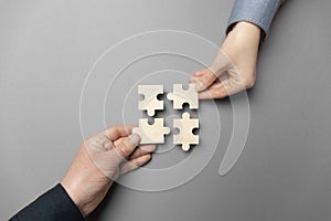 Two hands connect puzzles on a grey background. Cooperation and teamwork in business. Collaboration people for success photo