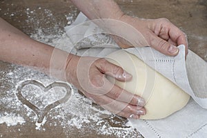 Two hands covering bread dough with towel