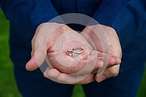 two hands cupping together with two wedding rings.