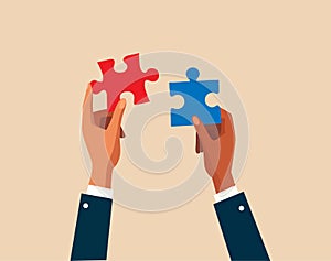 Two hands dressed in business attire are poised to connect two puzzle pieces, problem-solving, or the coming together of ideas.