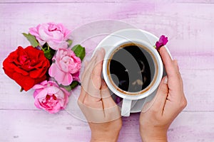 Two hands embracing cup of coffee with flower