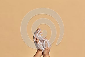 Two hands with hand soap foam on colorful background with copy space