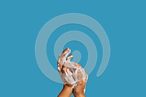 Two hands with hand soap foam on colorful background with copy space