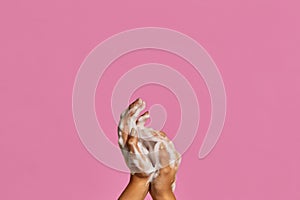 Two hands with hand soap foam on colorful background with copy space