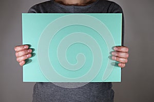 Two hands holding blue paper sheet