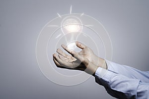 Two hands holding the drawing light bulb that is illuminating. Creative protecting patents and ideas concept photo