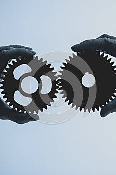 Two hands holding iron, metal cogwheel together