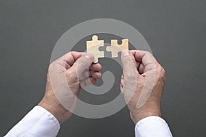 Two hands holding jigzaw puzzles. Black color background