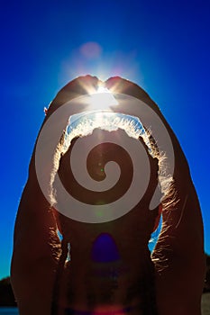 Two hands holding the sun on a blue sky background