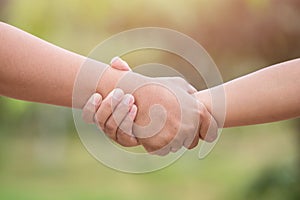 Two hands holding together. Help or support concept. On green bl