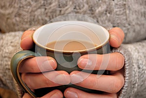 Two hands keeping warm, holding a hot cup of tea or coffee