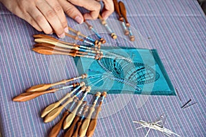 Two hands make bobbin lace on pillow