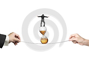 Two hands pulling rope businessman balancing on hourglass