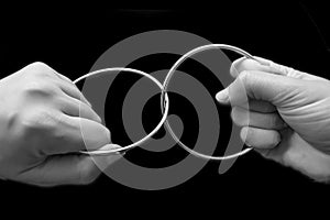 Two hands pulling rings apart that are joined together photo