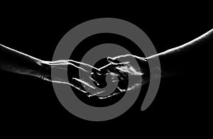 Two hands reaching toward. Helping hand outstretched for salvation on  black background. Close up of man and