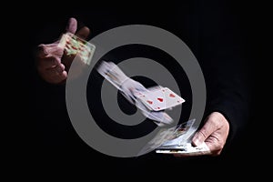 Two hands shuffle falling cards with motion blur against a black