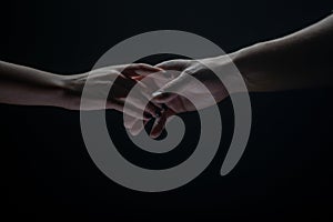 Two hands stretch each other, black background. Couple in love holding hads, close up. Helping hand, support, friendship