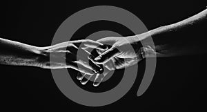 Two hands stretch each other, black background. Couple in love holding hads, close up. Helping hand, support, friendship