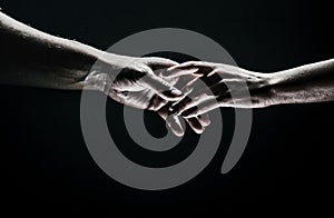 Two hands stretch each other, black background. Couple in love holding hads, close up. Helping hand, support, friendship