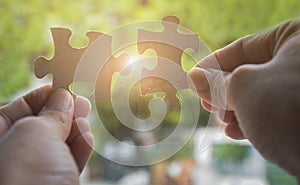 Two hands trying to connect couple jigsaw puzzle piece with sunlight effect. Business solutions, success and strategy concept photo