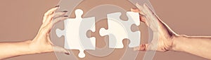 Two hands trying to connect couple puzzle piece on gray background. Teamwork concept. Holding puzzle. Closeup hand of