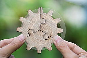 Two hands trying to connect couple puzzle piece with green background. symbol of association and connection. business strategy.