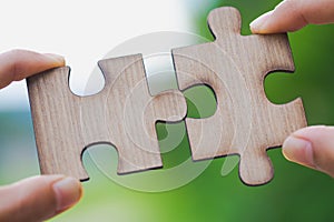Two hands trying to connect couple puzzle piece with green background. symbol of association and connection. business strategy.