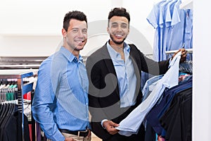 Two Handsome Business Man Fashion Shop, Happy Smiling Mix Race Friends Customers Choosing Clothes Shirts In Retail Store