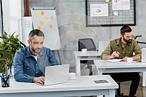 two handsome businessmen working at laptops