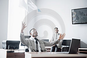 Two handsome cheerful african american businessman celebration successful with throwing paper in workplace