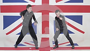 Two handsome males in black leather motorcycle jackets synchronically dance.