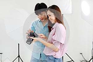 Two handsome man and beautiful woman wearing casual shirts smiling and looking or checking pictures in camera in indoor photo