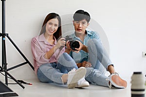 Two handsome man and beautiful woman wearing casual shirts smiling and looking or checking pictures in camera while sitting in