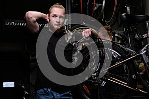 Two handsome stylish male working with a bicycle in a repair shop. Workers repair and mounts bike in a workshop