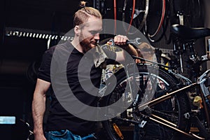 Two handsome stylish male working with a bicycle in a repair shop. Workers repair and mounts bike in a workshop