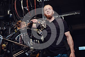 Two handsome stylish male working with a bicycle in a repair shop. Workers repair and mounts bike in a workshop