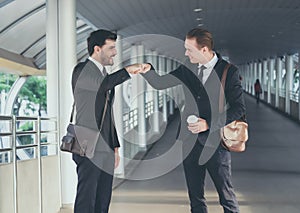 Two Handsome young Business men giving fist bump and talking on the city of the walk way.