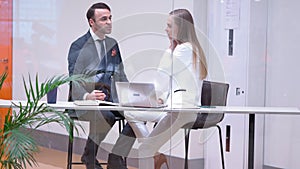 Two handsome young business people having a conversation while having talk sitting in their meeting room behind the